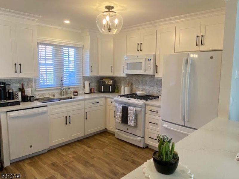 a kitchen with white cabinets and window