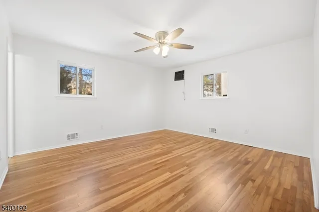 a view of a big room with wooden floor and windows