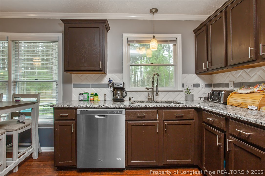 7156 Rockfish Road Raeford, NC 28376 - Photo 13 of 27 a kitchen with stainless steel appliances granite countertop wooden cabinets a sink a stove a window and cabinetry