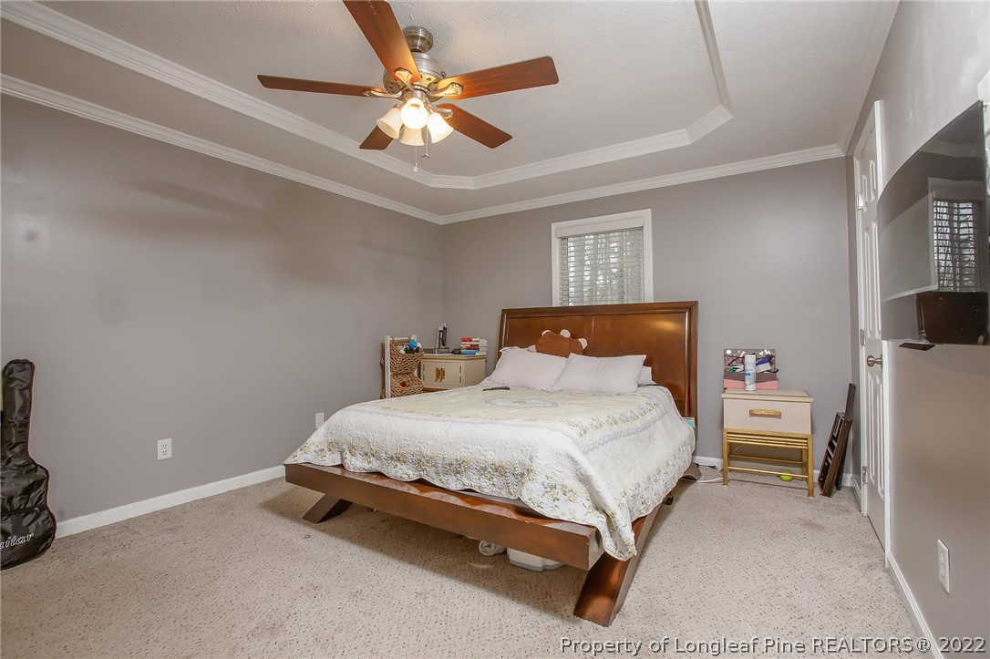 7156 Rockfish Road Raeford, NC 28376 - Photo 24 of 27 a bedroom with a bed and a chandelier