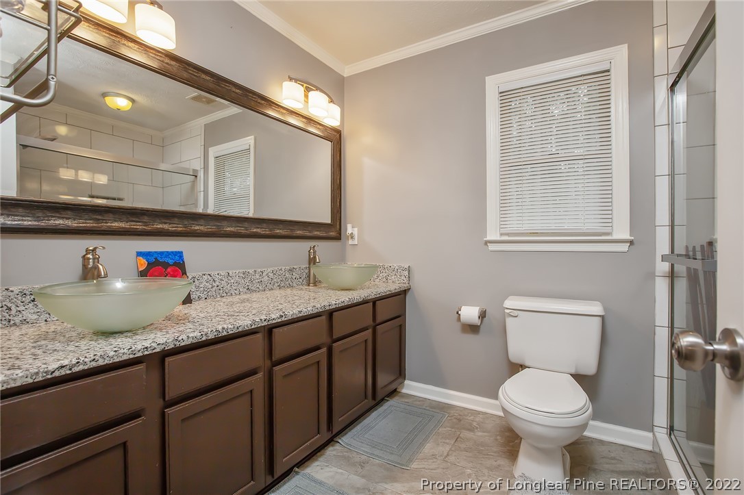 7156 Rockfish Road Raeford, NC 28376 - Photo 27 of 27 a bathroom with a granite countertop toilet sink and mirror