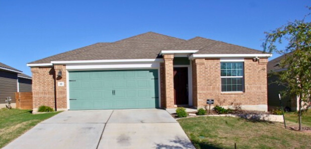 View of front of house with a garage, driveway, brick siding, and a front yard