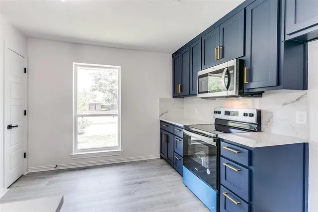 a kitchen with stainless steel appliances granite countertop a stove a microwave and a sink
