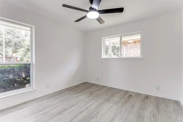 a view of empty room with wooden floor and fan
