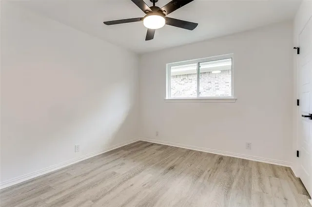 an empty room with a window and a ceiling fan