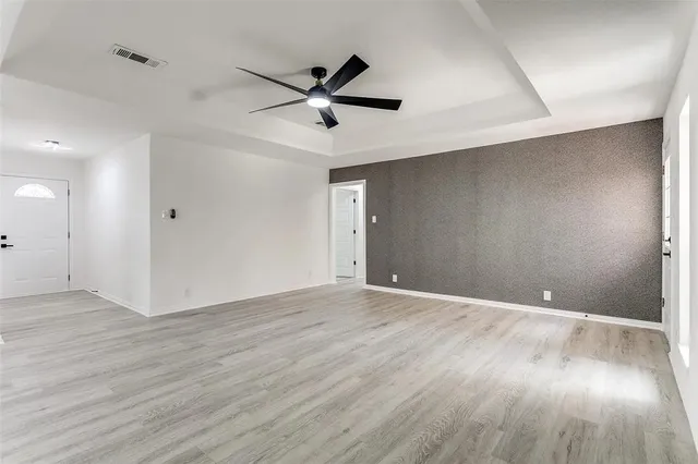 an empty room with wooden floor and a ceiling fan