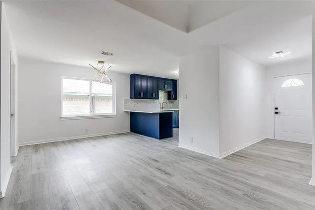 an empty room with wooden floor and chandelier