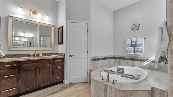 a bathroom with a tub a sink and a large mirror