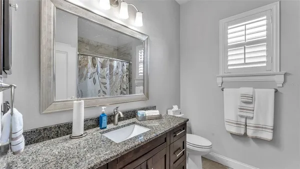 a bathroom with a granite countertop toilet sink and mirror
