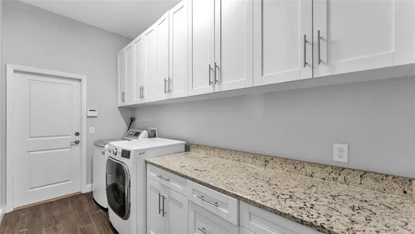 a utility room with granite countertop cabinets washer and dryer