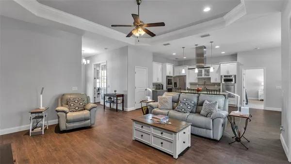 a living room with furniture kitchen view and a chandelier