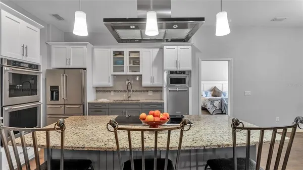 a kitchen with stainless steel appliances granite countertop a stove and white cabinets