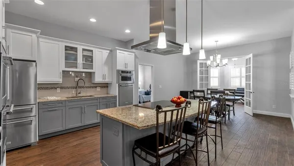 a kitchen with stainless steel appliances granite countertop a dining table chairs stove refrigerator and cabinets