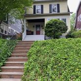 a view of a house with a small yard plants and large tree