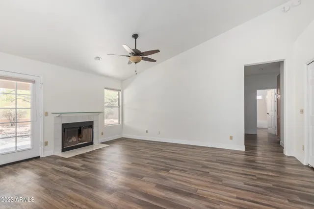 an empty room with wooden floor ceiling fan and windows
