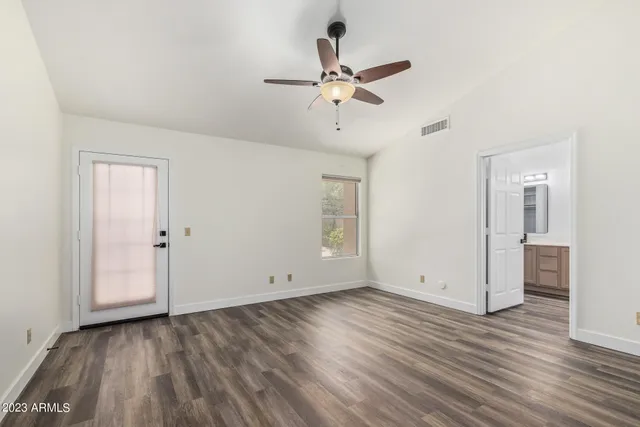an empty room with wooden floor and ceiling fan