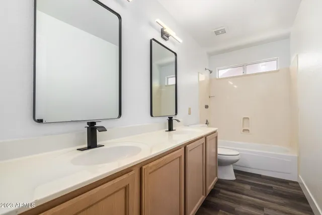 an empty room with wooden floor cabinet and windows