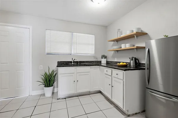 a kitchen with a refrigerator and white cabinets
