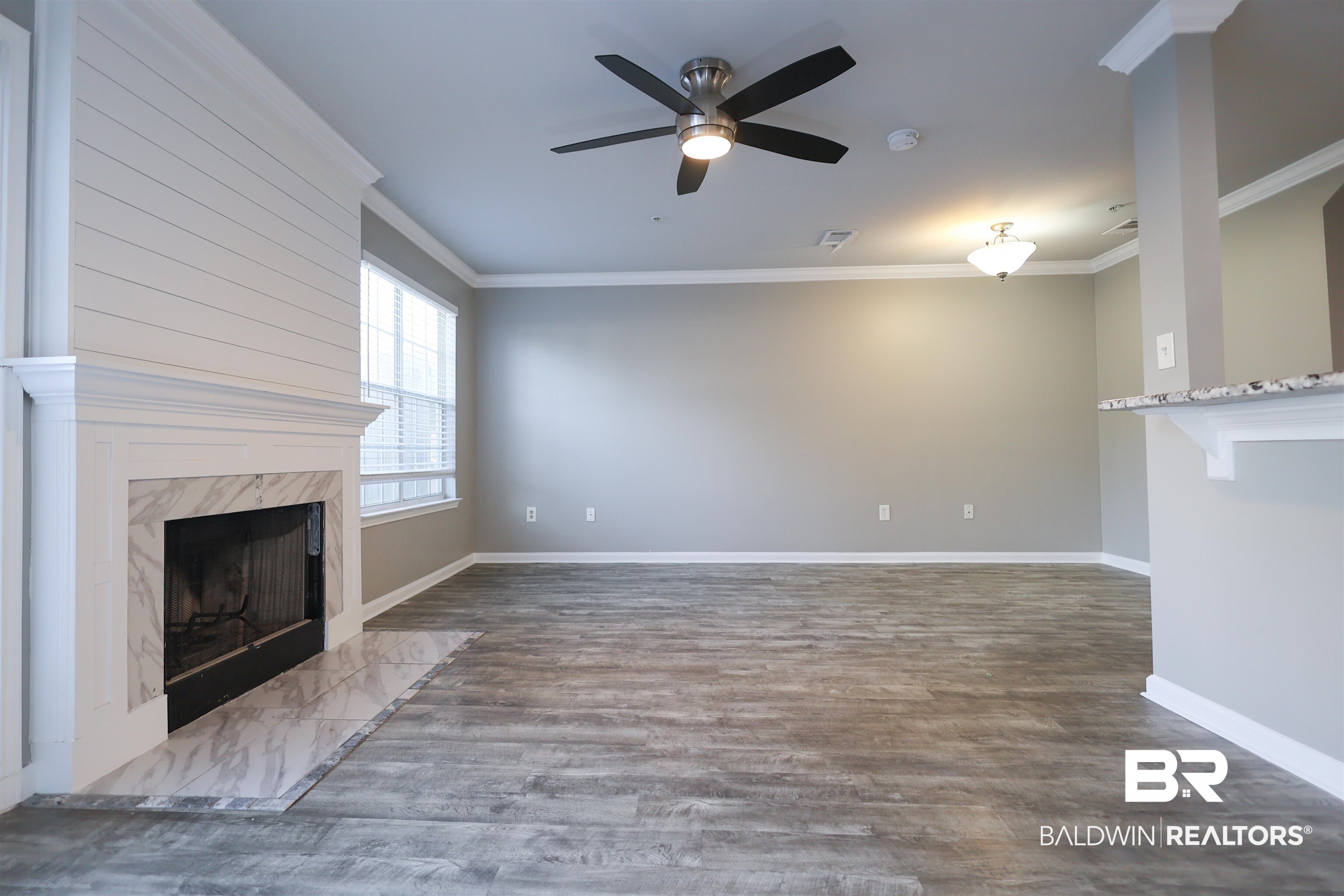 1517 Regency Road, Unit 125 Gulf Shores, AL 36542 - Photo 5 of 26 Unfurnished living room with a premium fireplace, ornamental molding, ceiling fan, and dark wood finished floors