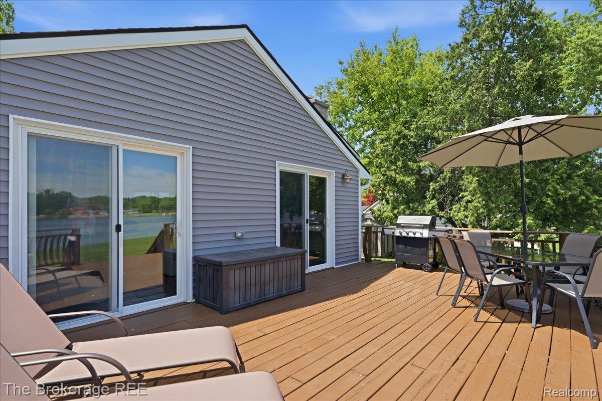 261 Reymont Road Waterford, MI 48327 - Photo 34 of 49 Expansive outdoor wood-finish deck featuring a full sliding glass door, a secondary glass-paneled door, and gray horizontal siding