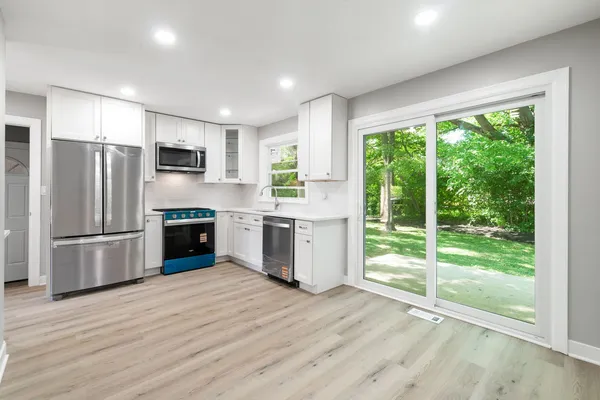 a kitchen with a refrigerator a stove top oven and a large window