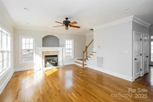 a view of a livingroom with a fireplace a ceiling fan and wooden floor