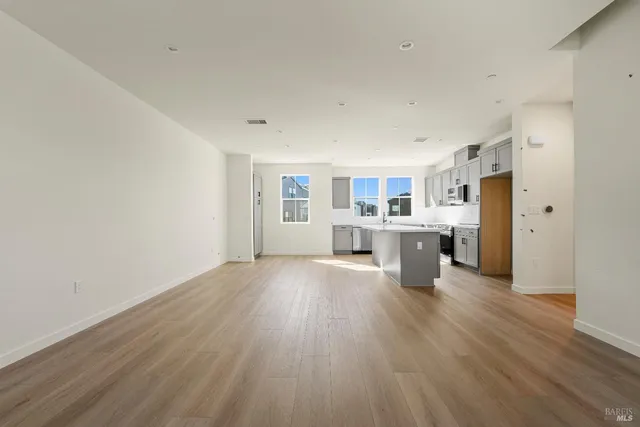 a open kitchen with stainless steel appliances granite countertop a dishwasher and a refrigerator with wooden floor