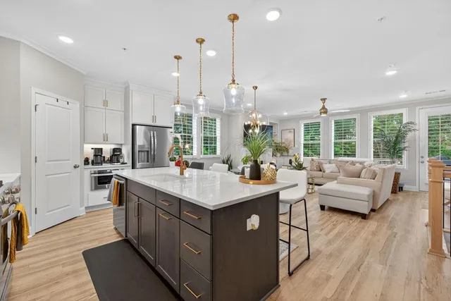 a kitchen with stainless steel appliances kitchen island granite countertop a dining table chairs and a refrigerator