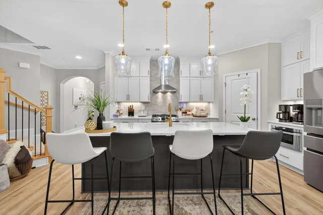 a kitchen with stainless steel appliances granite countertop a stove a sink dishwasher and white cabinets with wooden floor