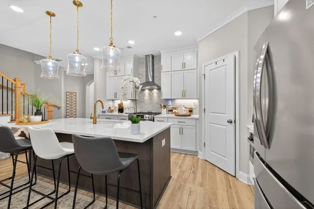 a large white kitchen with a large island oven a stove and a chandelier