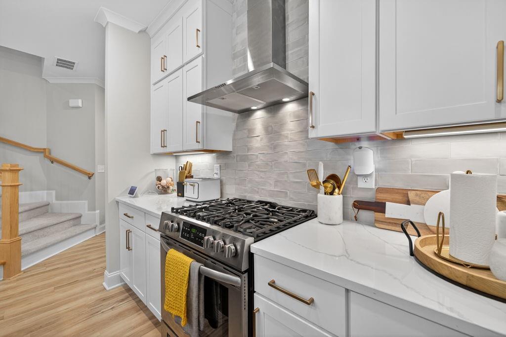 425 Retreat Lane Canton, GA 30114 - Photo 10 of 55 a kitchen with stainless steel appliances granite countertop a stove a sink dishwasher and white cabinets with wooden floor