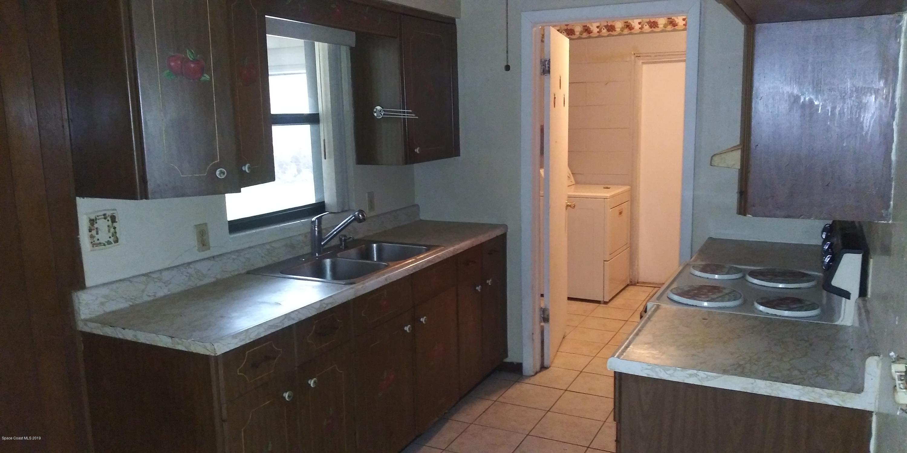 2465 Dolphin Road Titusville, FL 32780 - Photo 23 of 40 a kitchen with a sink and a refrigerator