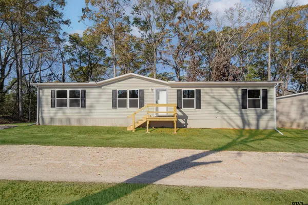 a front view of a house with a yard and trees