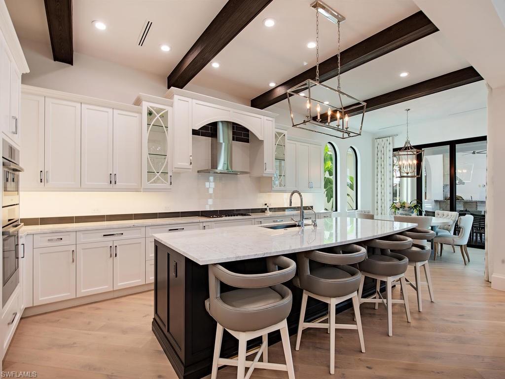 16868 Brightling Way Naples, FL 34110 - Photo 7 of 35 a kitchen with granite countertop a table chairs sink and cabinets