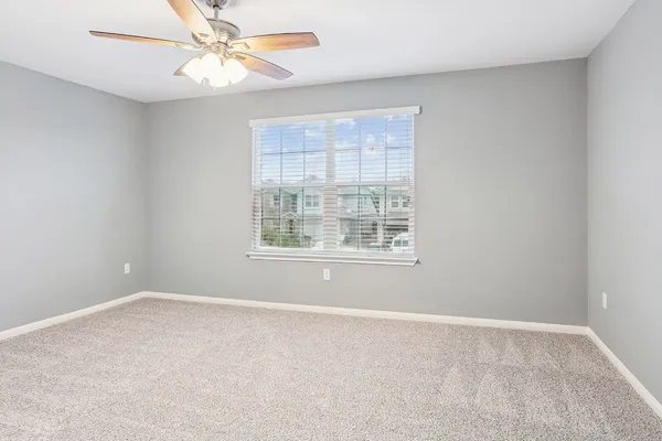 an empty room with a window and a fan