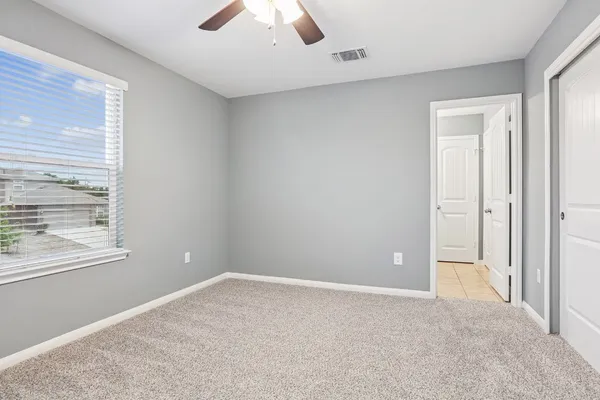 an empty room with chandelier fan and windows