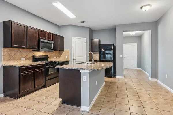 a kitchen with stainless steel appliances kitchen island granite countertop a stove microwave and cabinets