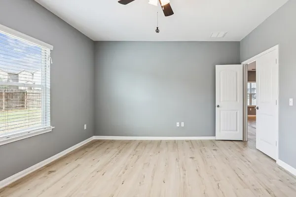 an empty room with wooden floor and windows