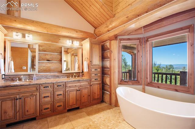 616 Summit Road Hartsel, CO 80449 - Photo 26 of 50 Bathroom with vaulted ceiling, rustic walls, dual bowl vanity, tile patterned floors, and a bath