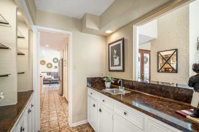 a kitchen with stainless steel appliances granite countertop a refrigerator a sink dishwasher and white cabinets with wooden floor