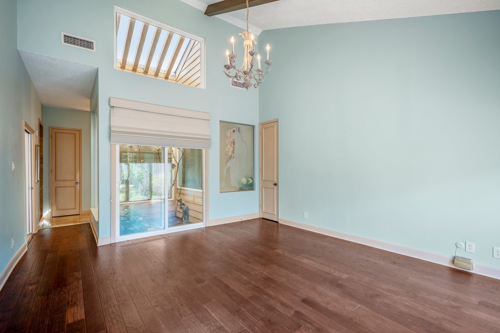 1306 Riverview Court Houston, TX 77077 - Photo 27 of 44 The primary bedroom features wood floors, sliding doors that open to the expansive patio, and serene views of the lighted fountain, while an atrium with a skylight fills the space with natural light.
