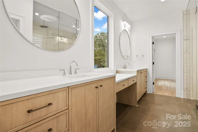 a spacious bathroom with a double vanity sink a mirror and a shower
