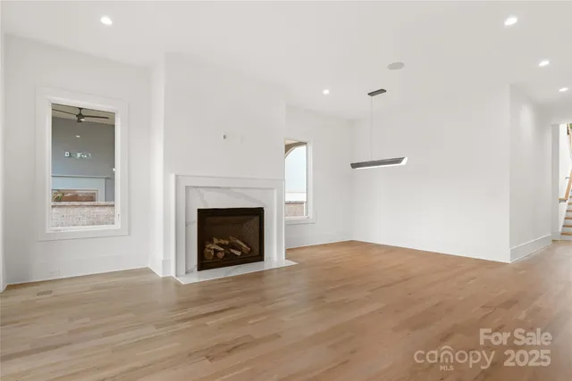 a view of an empty room with wooden floor fireplace and a window