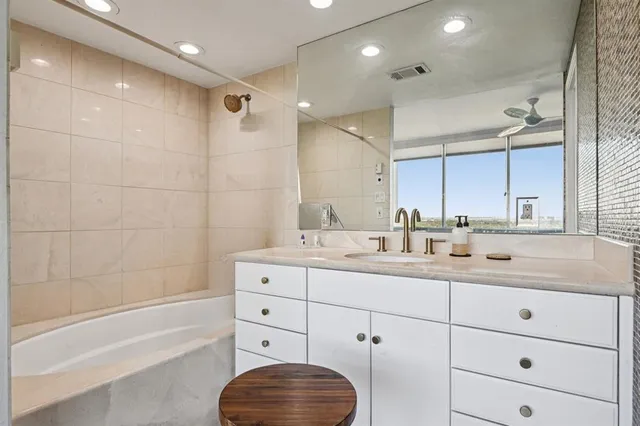 a bathroom with a granite countertop sink mirror and bathtub