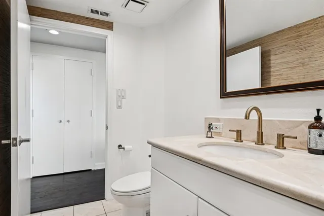 a bathroom with a granite countertop sink a toilet and a mirror
