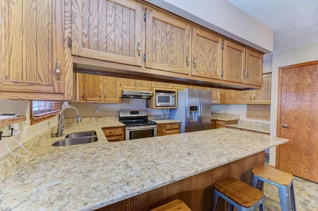 a kitchen with stainless steel appliances granite countertop a stove a sink and a microwave