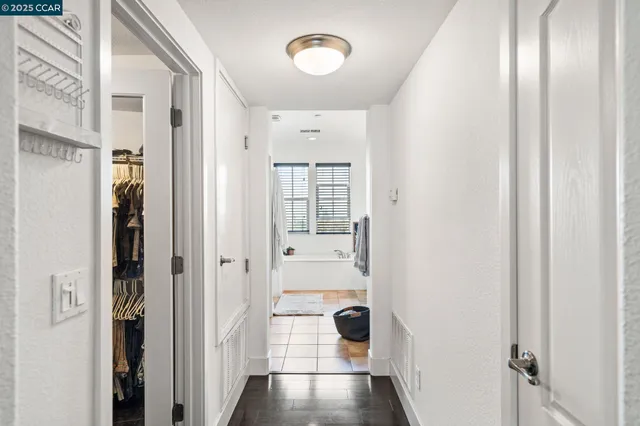 a view of a hallway with wooden floor and a bathroom