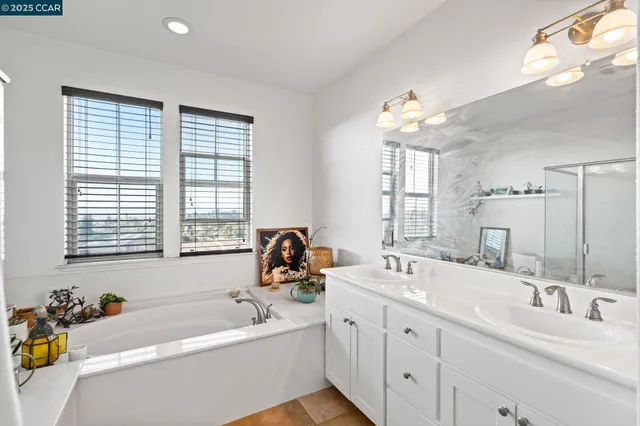 a bathroom with a tub a sink double vanity and a mirror