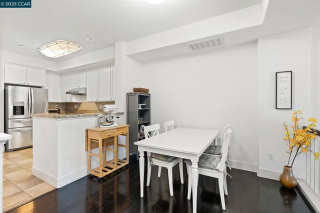 a kitchen with stainless steel appliances a dining table chairs and refrigerator