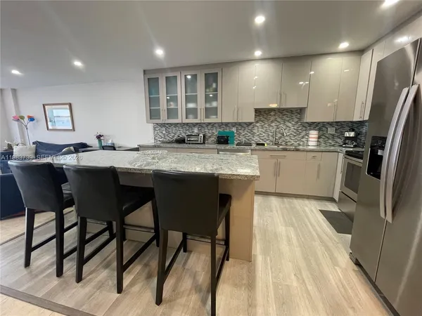 a kitchen with stainless steel appliances granite countertop a table chairs sink refrigerator and cabinets